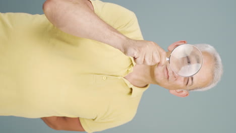 Vertical-video-of-Man-looking-at-camera-with-magnifying-glass.